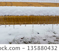 A row of small icicles on a wooden fence under a layer of snow. 135880432