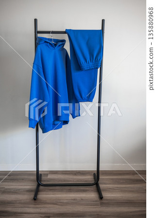 Hoodie and sweatpants displayed on a simple rack inside a room Hoodie and sweatpants displayed on a simple rack inside a room 135880968