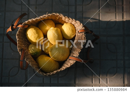 Fresh lemons in a woven basket placed on a stone surface during daylight Fresh lemons in a woven basket placed on a stone surface during daylight 135880984