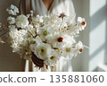 Flower arrangement held by person in bright indoor space during daylight hours 135881060