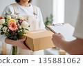 Delivery of a box and flowers by a person in an indoor setting 135881062