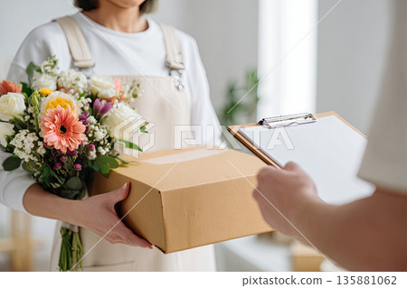 Delivery of a box and flowers by a person in an indoor setting 135881062