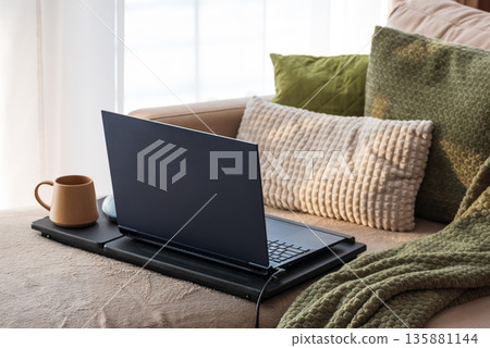 Laptop and Coffee Mug on Lap Desk. Cozy Morning Home Workspace with Green Accents Laptop and Coffee Mug on Lap Desk. Cozy Morning Home Workspace with Green Accents 135881144