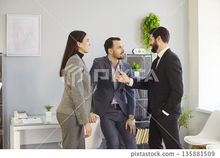 Office people talk, colleagues wearing business attire, engaged in informal conversation, discussion 135881509