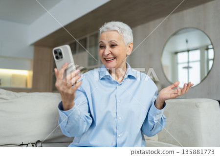 Happy middle aged senior woman talking with smartphone on video call with friends family. Laughing mature old senior lady grandmother having fun talking speaking with grown up children online Happy middle aged senior woman talking with smartphone on video call with friends family. Laughing mature old senior lady grandmother having fun talking speaking with grown up children online 135881773