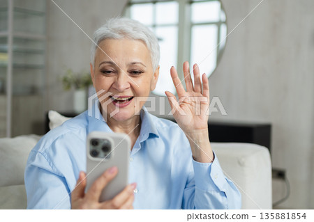 Happy middle aged senior woman talking with smartphone on video call with friends family. Laughing mature old senior lady grandmother having fun talking speaking with grown up children online Happy middle aged senior woman talking with smartphone on video call with friends family. Laughing mature old senior lady grandmother having fun talking speaking with grown up children online 135881854