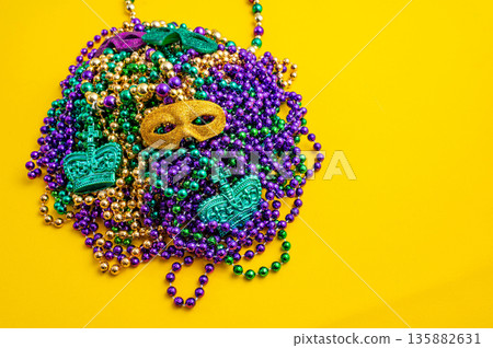 Mardi Gras beads in glittering yellow, green, purple, and gold. Sparkling festive background for Mardi Gras in traditional colors. 135882631