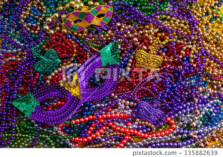 Mardi Gras beads in glittering yellow, green, purple, and gold. Sparkling festive background for Mardi Gras in traditional colors. 135882639