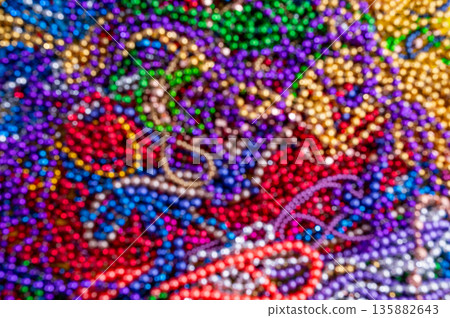 Mardi Gras beads in glittering yellow, green, purple, and gold. Sparkling festive background for Mardi Gras in traditional colors. 135882643