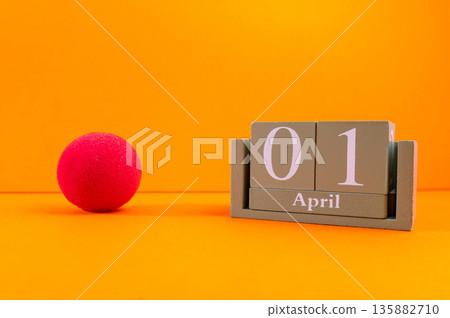 Calendar with clown wig, funny glasses and sequins on brown background. April Fools Day Calendar with clown wig, funny glasses and sequins on brown background. April Fools Day 135882710