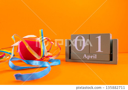 Calendar with clown wig, funny glasses and sequins on brown background. April Fools Day Calendar with clown wig, funny glasses and sequins on brown background. April Fools Day 135882711