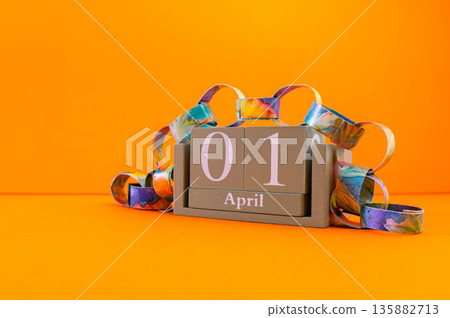 Calendar with clown wig, funny glasses and sequins on brown background. April Fools Day Calendar with clown wig, funny glasses and sequins on brown background. April Fools Day 135882713