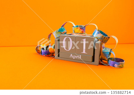 Calendar with clown wig, funny glasses and sequins on brown background. April Fools Day Calendar with clown wig, funny glasses and sequins on brown background. April Fools Day 135882714