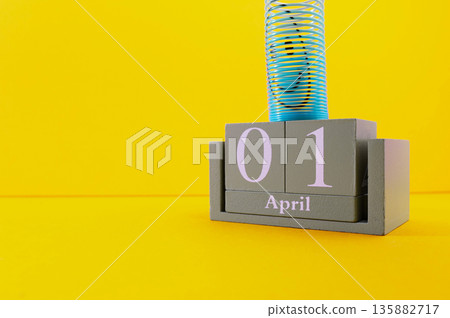 Calendar with clown wig, funny glasses and sequins on brown background. April Fools Day 135882717