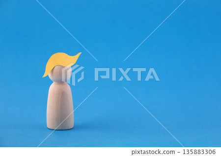 Wooden man figurine with paper yellow hair on blue background that may depicting US President Donald Trump 135883306