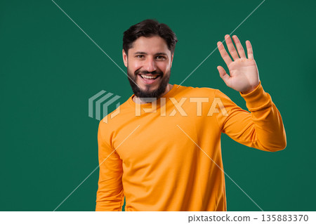 Friendly 30s aged man Waving Hand - Hello, Hi, salute, chao. Greetings on green Friendly 30s aged man Waving Hand - Hello, Hi, salute, chao. Greetings on green 135883370