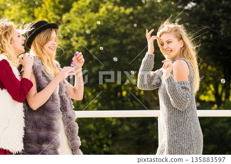 Women friends blowing soap bubbles. Women friends blowing soap bubbles. 135883597