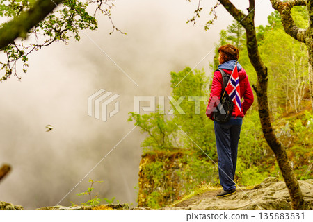 Tourist with norwegian flag in hazy mountains 135883831
