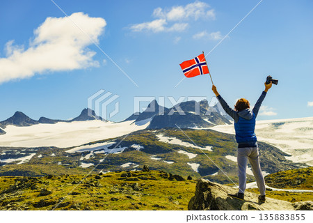 Tourist with camera and flag in Norway mountains 135883855