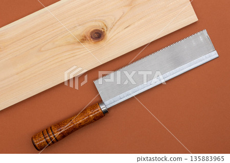 Saw and cypress board on brown background DIY/woodworking Saw and cypress board on brown background DIY/woodworking 135883965