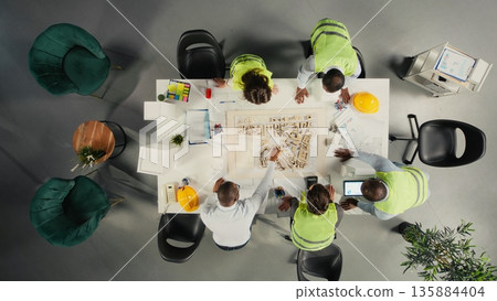 Top down view of doctors team in a collaborative meeting discussing therapy, diagnostics and clinical coordination. Modern healthcare staff focuses on communication and patient health. 135884404