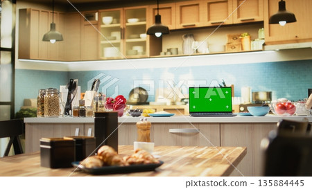 Green screen laptop in empty kitchen with island and modern appliances, setup captures a cozy inviting atmosphere of home cooking and tasty homemade food ready to bake. Kitchenware. Green screen laptop in empty kitchen with island and modern appliances, setup captures a cozy inviting atmosphere of home cooking and tasty homemade food ready to bake. Kitchenware. 135884445