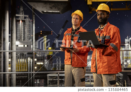 Environmental engineers on offshore platform conducting oil rig inspections, monitoring petroleum extraction to ensure efficient drilling operations within the marine oil industry activity. Environmental engineers on offshore platform conducting oil rig inspections, monitoring petroleum extraction to ensure efficient drilling operations within the marine oil industry activity. 135884465