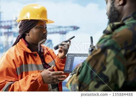 Naval unit conducting maritime interdiction operations around drilling sites using tablet to visualize infrastructure. Army soldier on drilling barge prevents piracy using device to make security plan 135884488