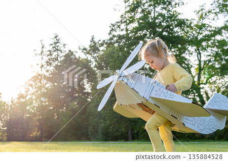 Cardboard pilot. Girl dress-up play child. Park dream aviation outdoor. 135884528