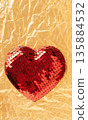 Red sequin heart symbolizing love on golden foil 135884532
