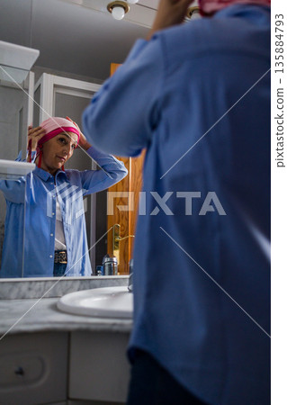 Woman with cancer adjusting headscarf embracing beauty 135884793