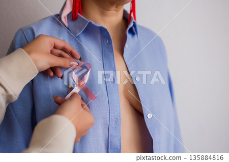Attaching pink ribbon promoting breast cancer awareness month Attaching pink ribbon promoting breast cancer awareness month 135884816