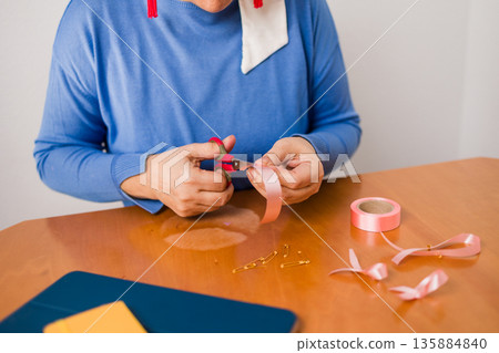 Woman crafting pink ribbon for breast cancer awareness Woman crafting pink ribbon for breast cancer awareness 135884840