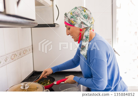 Woman with cancer cooking fresh vegetables in kitchen Woman with cancer cooking fresh vegetables in kitchen 135884852