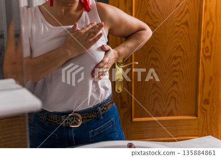 Woman performing breast self examination for cancer detection 135884861