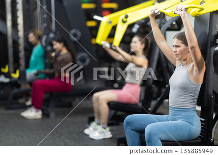 Determined young woman training upper body muscles Determined young woman training upper body muscles 135885949