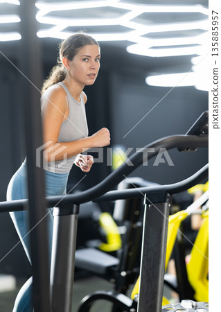 Young woman doing cardio exercises on treadmill 135885957