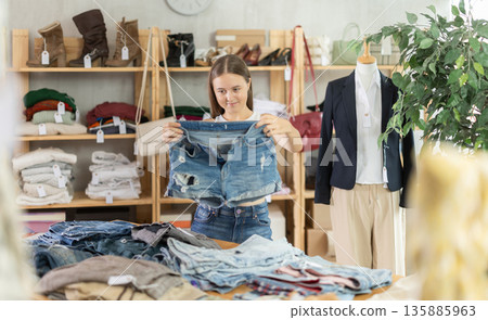 Teenage girl chooses denim shorts in store Teenage girl chooses denim shorts in store 135885963