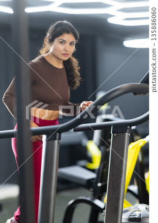 Sportive Latina girl training on treadmill in gym Sportive Latina girl training on treadmill in gym 135886060