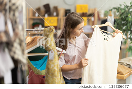 Teenage girl choosing dress in clothing store Teenage girl choosing dress in clothing store 135886077