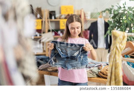 Teenage girl chooses denim shorts in store 135886084