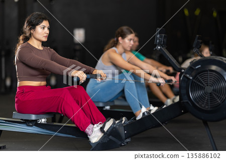 Latina woman doing an exercise on a rowing machine 135886102
