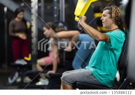 Determined middle-aged man training upper body muscles Determined middle-aged man training upper body muscles 135886112