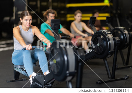 Woman doing cardio workout on rowing machine 135886114
