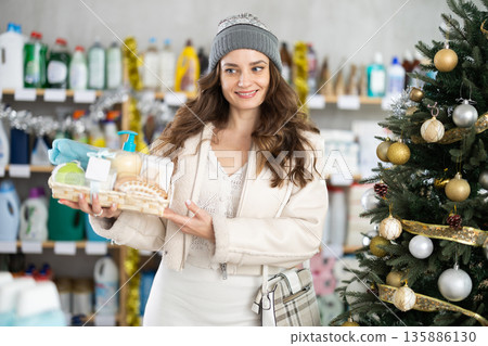 In household chemicals store, woman examines composition of shower cosmetic kit, X Mas gift set In household chemicals store, woman examines composition of shower cosmetic kit, X Mas gift set 135886130