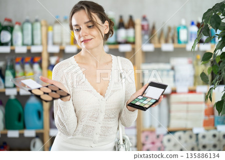 Woman purchases household chemicals in store and chooses eye shadow pallet Woman purchases household chemicals in store and chooses eye shadow pallet 135886134