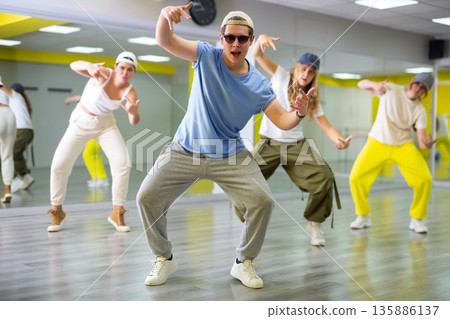 Group of young confident teenagers in casual clothes dancing together during exercise in class 135886137