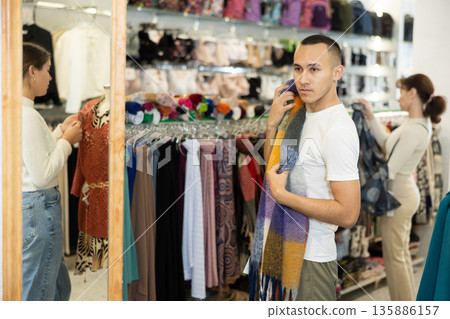 Young man choosing scarf in store Young man choosing scarf in store 135886157