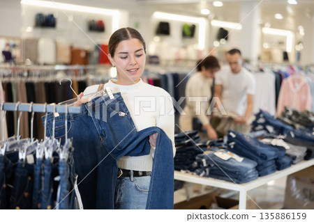 Young girl choosing blue jeans in clothing store Young girl choosing blue jeans in clothing store 135886159