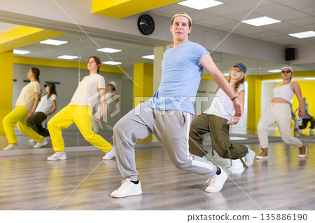 Teenage dancers, young people practicing modern dance styles together in spacious studio with mirrors Teenage dancers, young people practicing modern dance styles together in spacious studio with mirrors 135886190